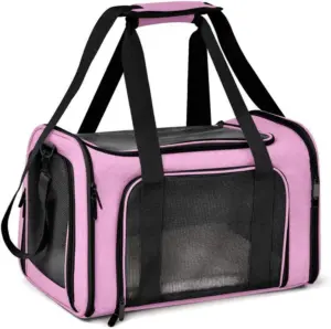 A pink pet carrier bag with black accents, featuring mesh ventilation windows, multiple black straps, and zippers, designed for pet transportation, set against a white background.